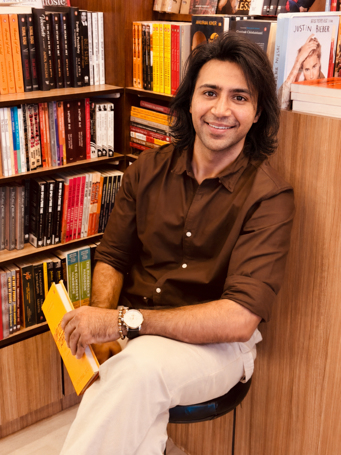 Mohit Mordani seated with a book in front of bookshelves